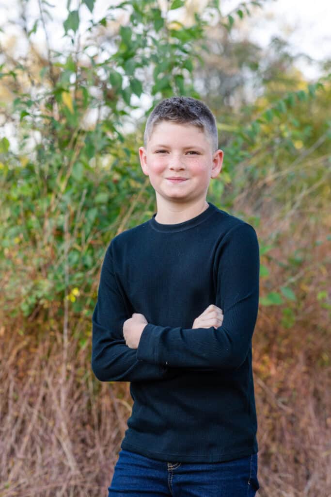 10 year old boy with black shirt crosses his arms and smiles